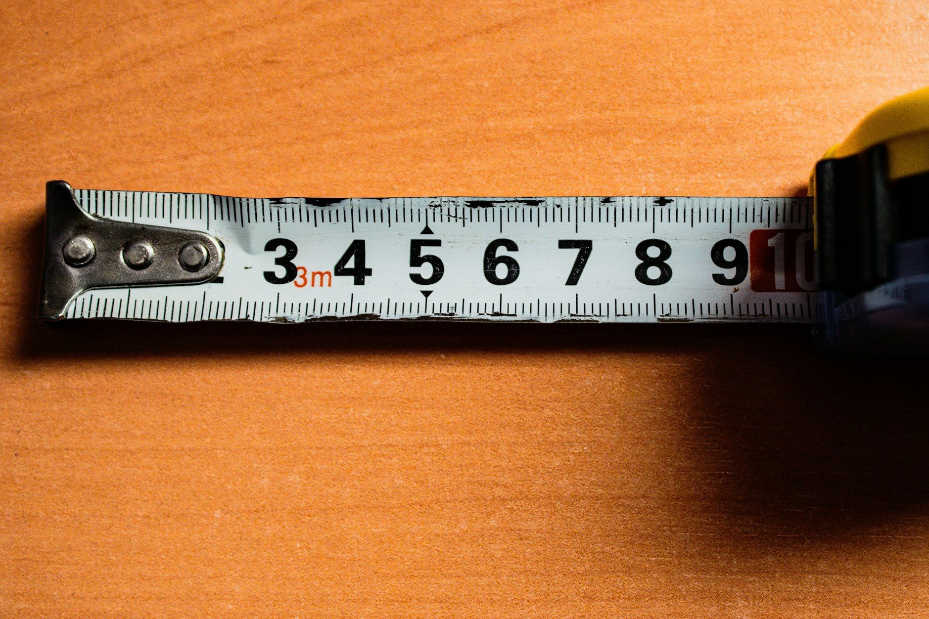 A steel tape measure pulled out across a timber bench, its yellow case at one end